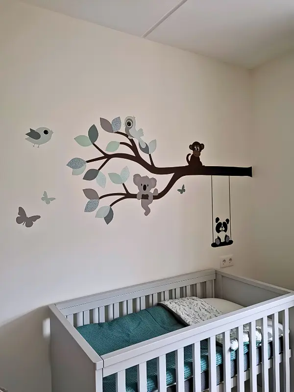 Neutrale groene babykamer met een vrolijke dieren tak behangsticker